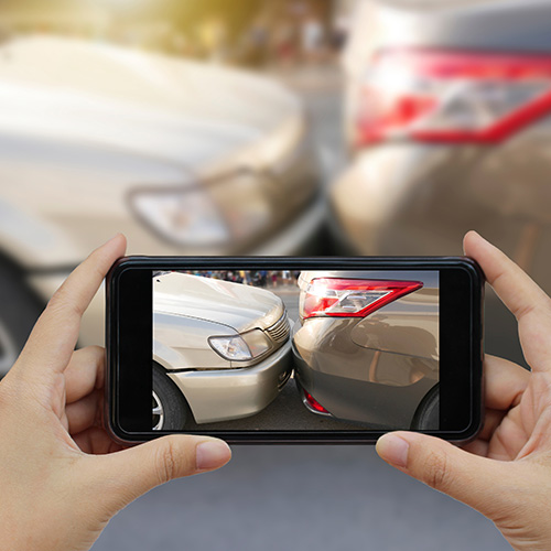 Person holding a camera phone taking photo of car crash